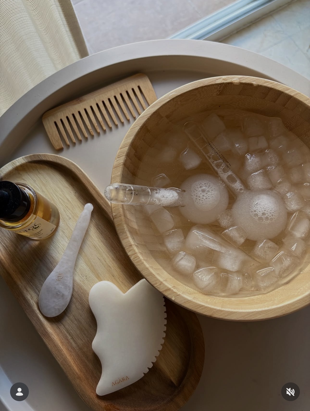 Bandeja de madera con bol de agua helada, gua-sha, cuchara de cuarzo, gotero y herramientas faciales