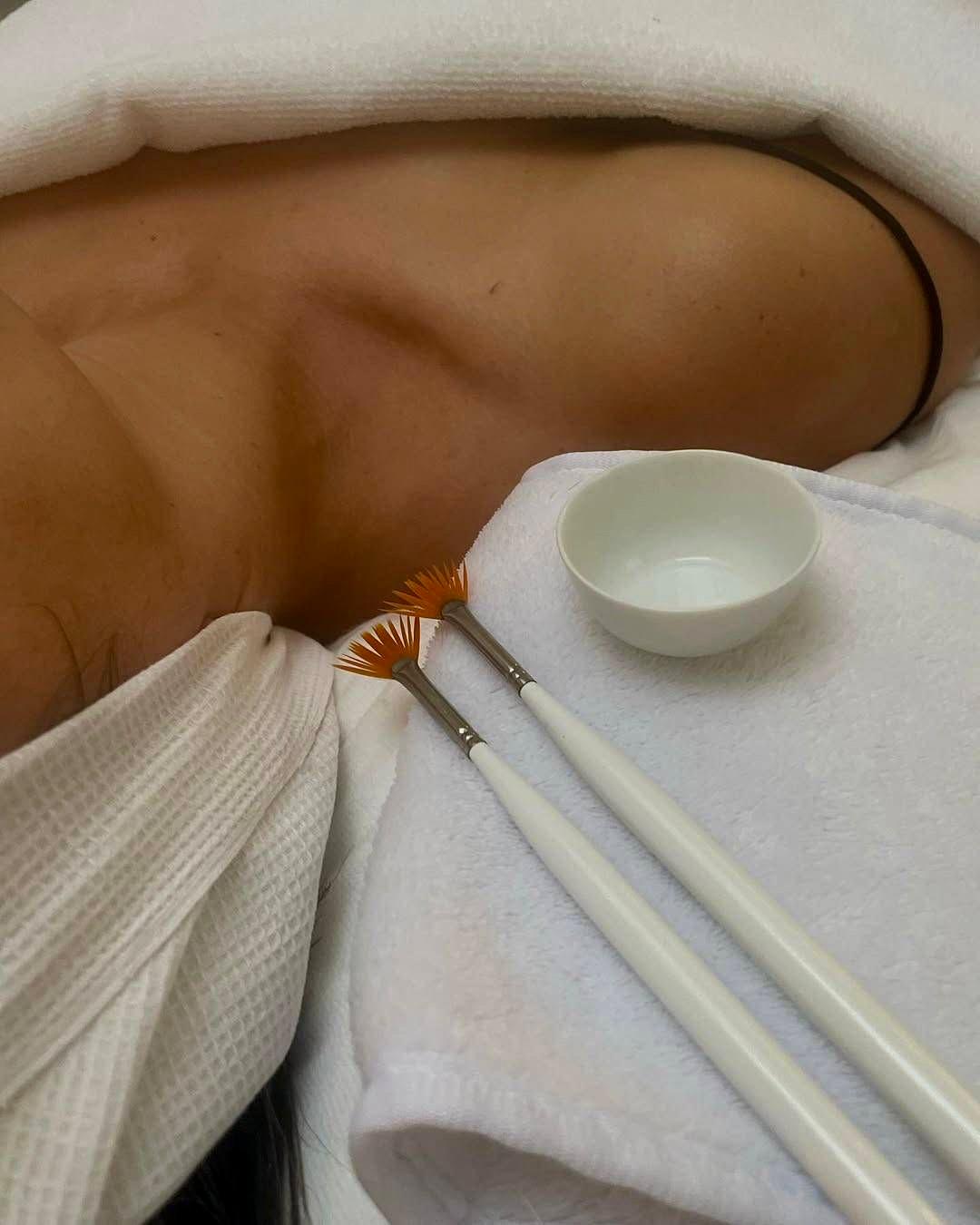 Pinceles profesionales y bol con producto sobre una toalla, listos para aplicar un peeling